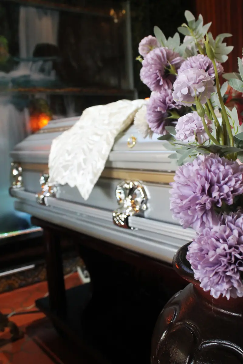 Ataúd plateado con flores lilas en una capilla de Hosanna
