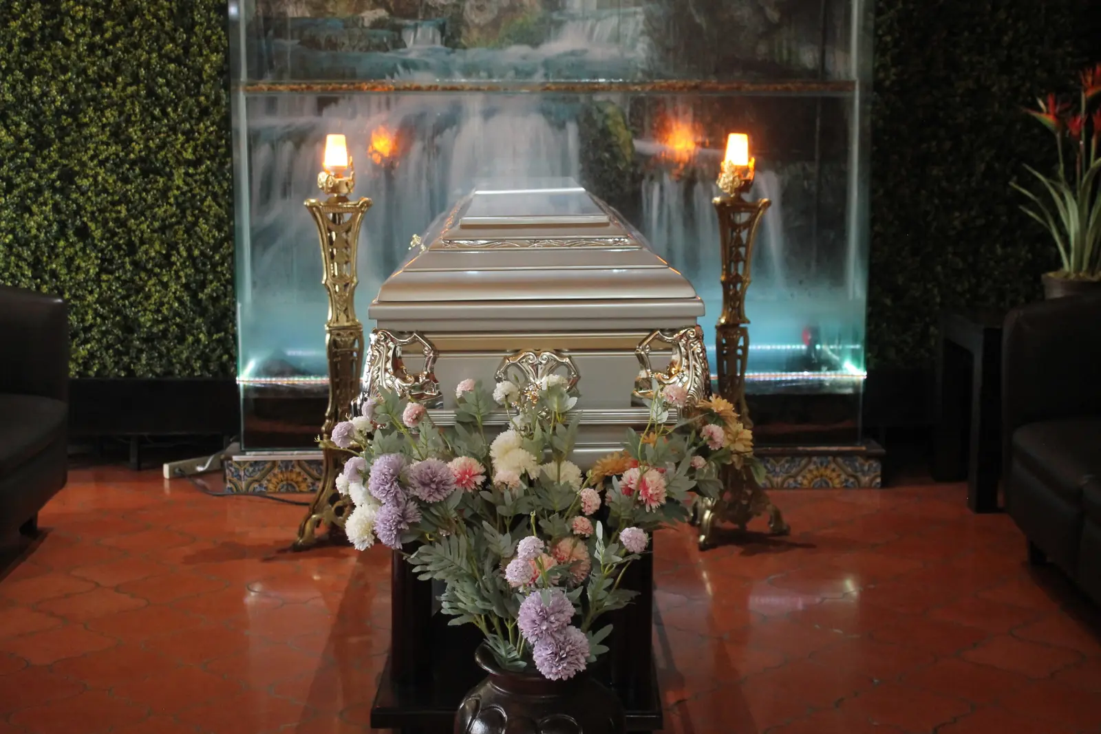Capilla de Hosanna: ataúd plateado entre dos candelabros dorados encendidos, frente a una cascada de agua