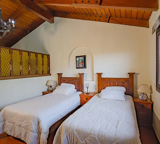 Habitación de reposo con dos camas individuales y techo de madera