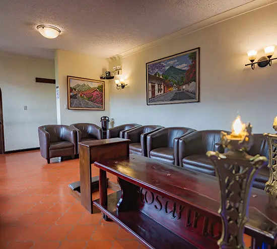 Sala con sillones de cuero, cuadros de paisajes y un candelabro encendido